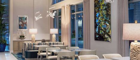 A modern hotel lobby with a seating area, large windows, and artwork on the walls.