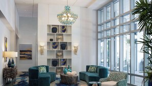 A spacious lobby with a large window, a chandelier, and a variety of decorative items on shelves.