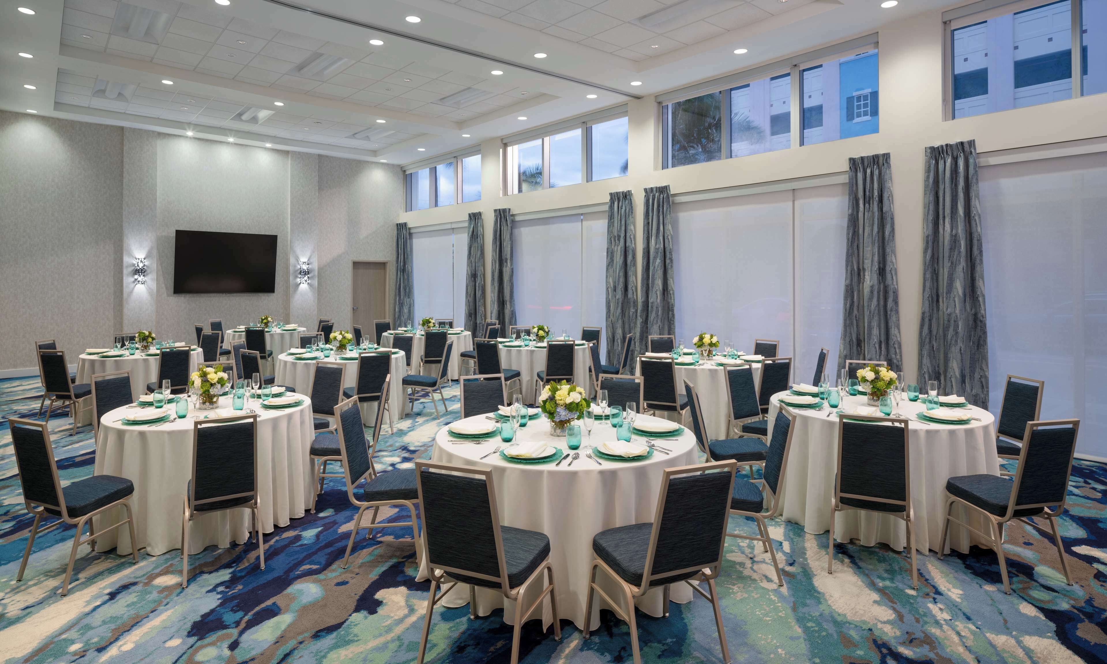 A conference room with multiple round tables, each set with chairs, plates, and glassware.