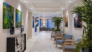 A hotel lobby with a reception desk, seating area, and artwork on the walls.