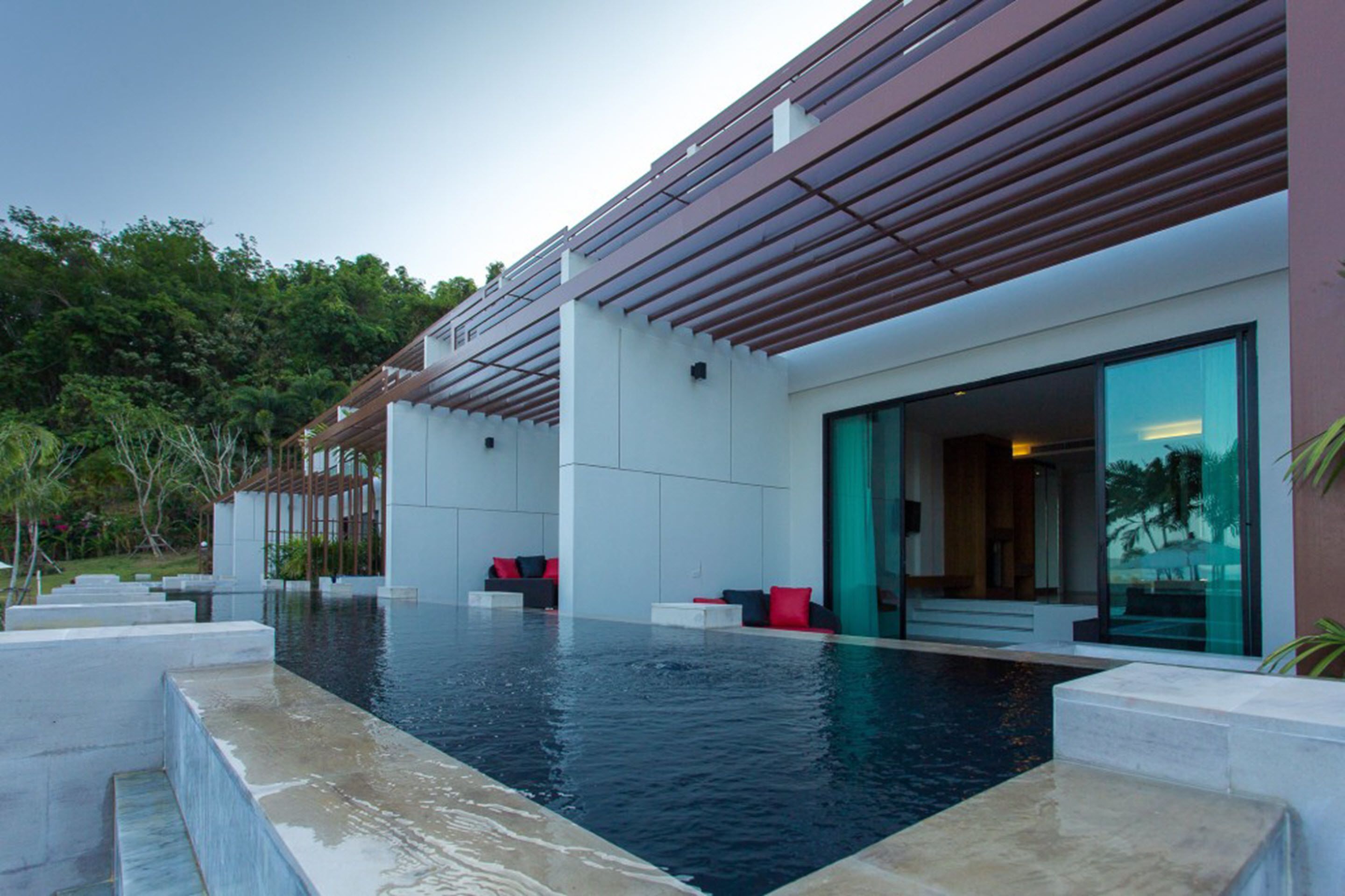 A modern building with a swimming pool, outdoor seating, and a glass entrance.