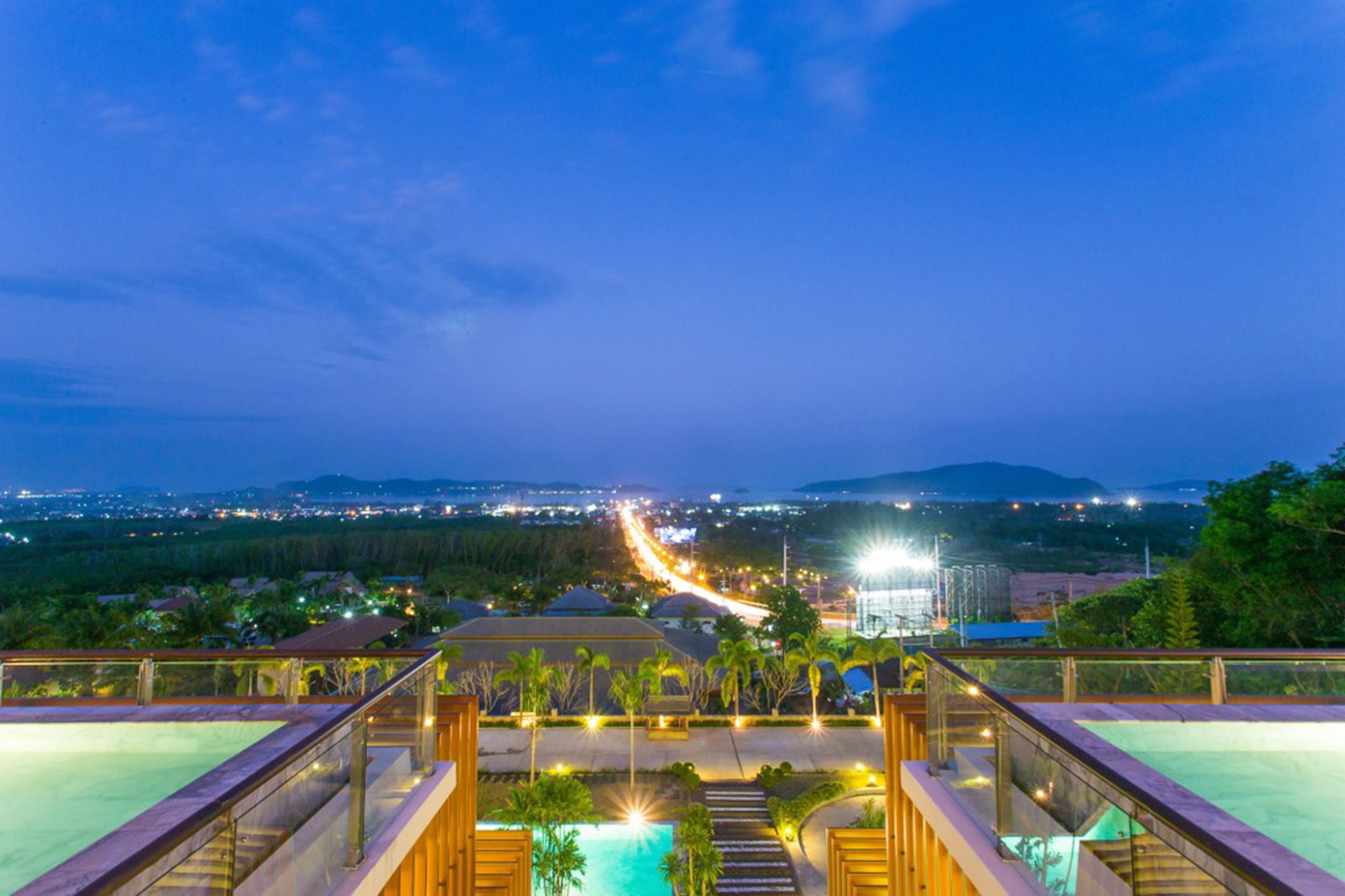 A resort pool with a view of a cityscape at dusk.