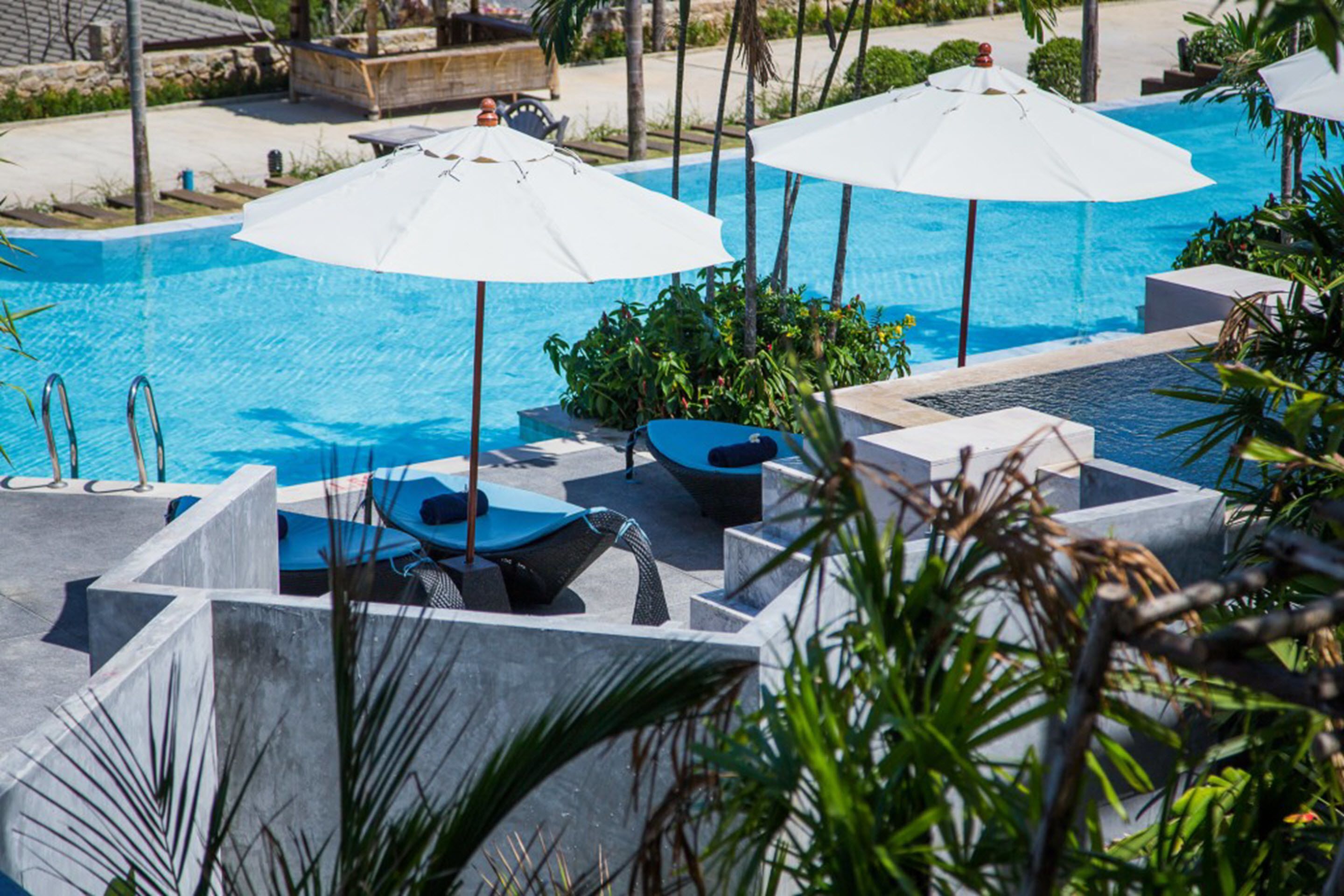 Un área de piscina con sillones de descanso y sombrillas.