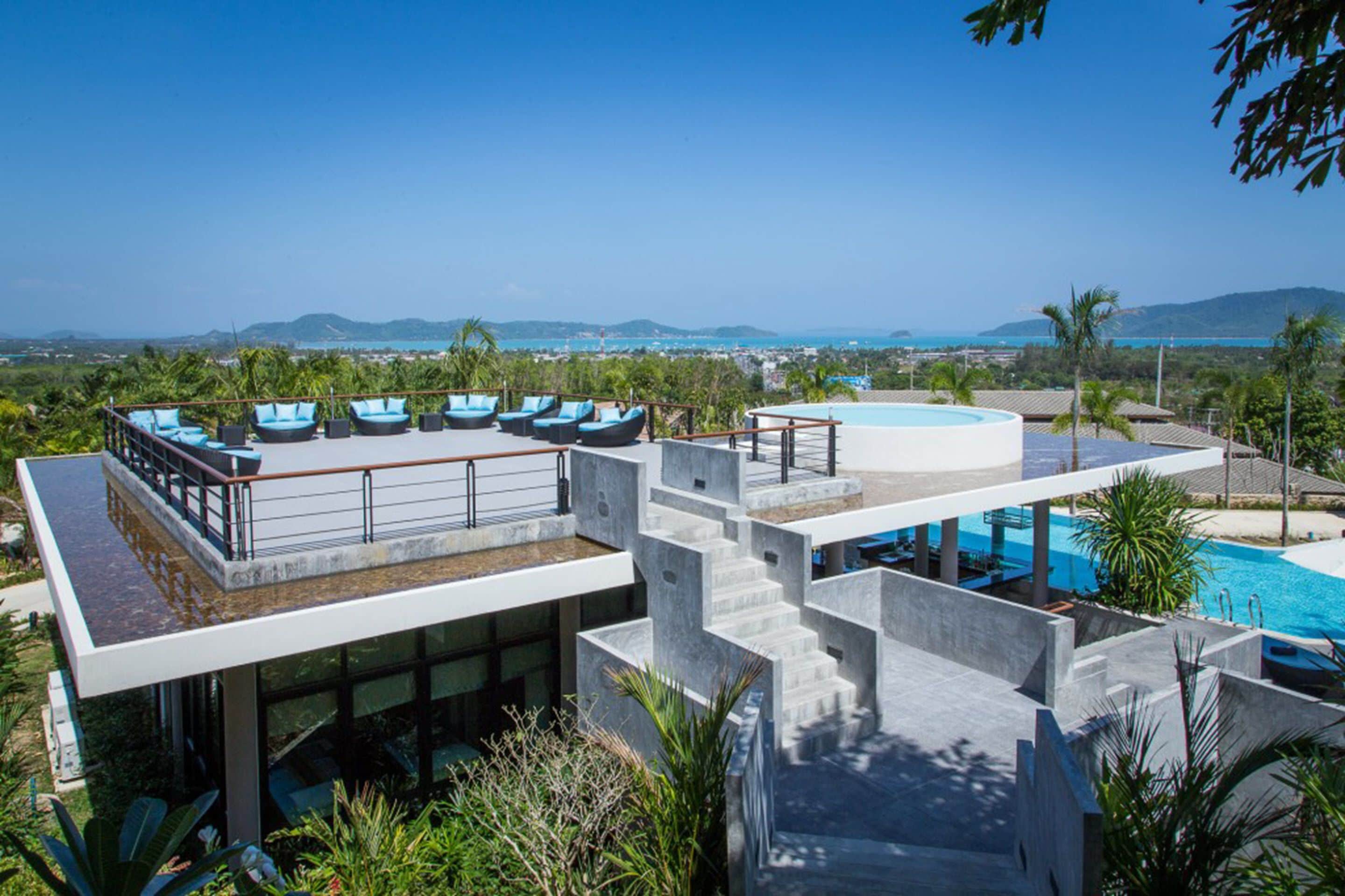 A rooftop pool area with lounge chairs and a view of the ocean.