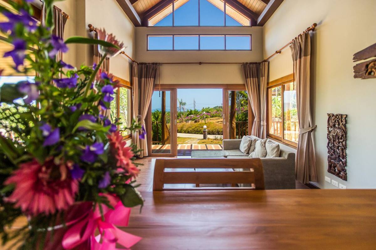A spacious room with a wooden bench, a sofa, and a large window offering a view of a garden.