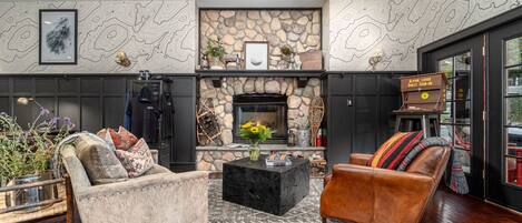 A modern living room with a stone fireplace, leather sofas, and a coffee table.