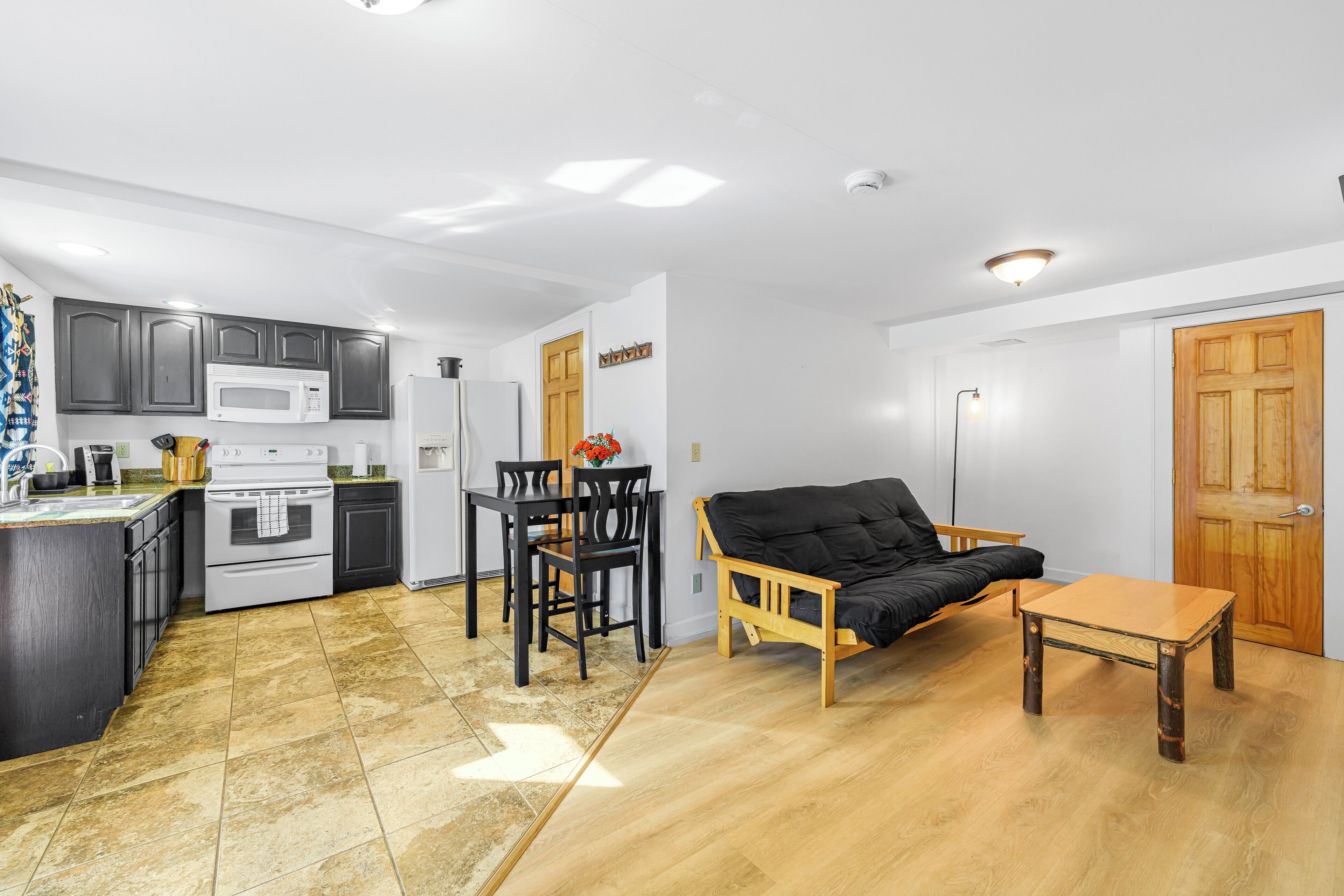 A compact kitchen with a dining area, a sofa, and a small table.