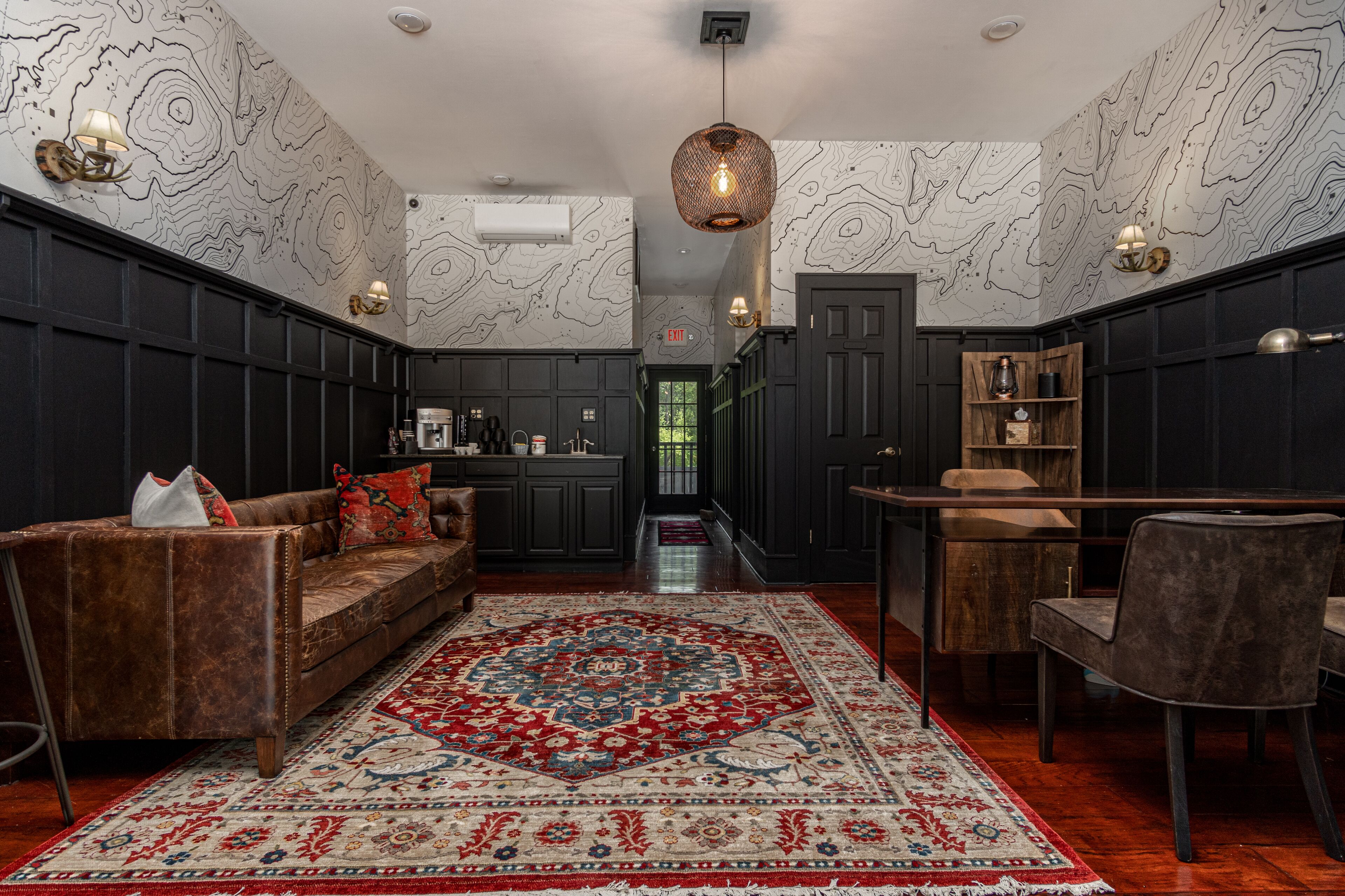 A modern kitchen with dark cabinetry, a central island, and a dining area with a table and chairs.