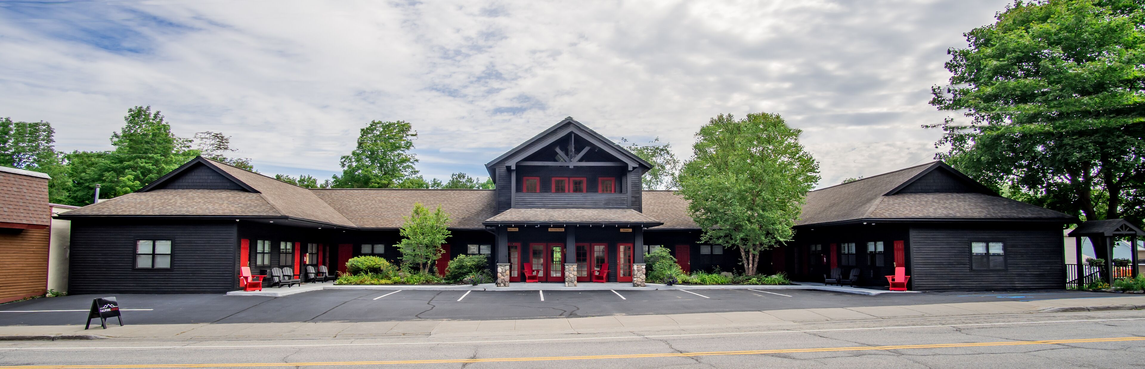 A building with a central entrance, two side wings, and a parking lot in front.