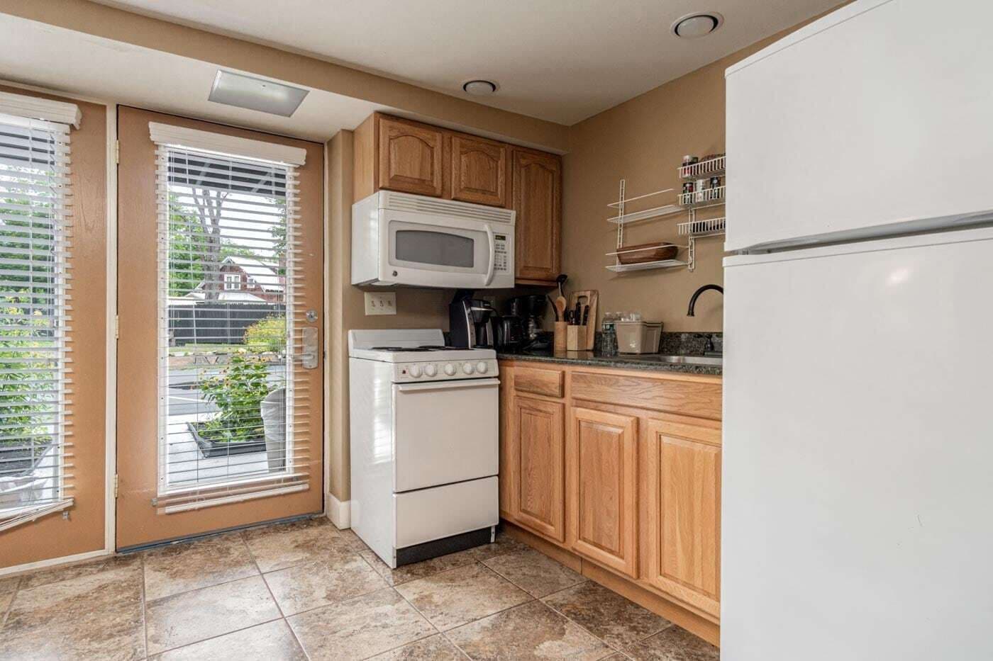 A compact kitchen with wooden cabinets, a white stove, a microwave, and a refrigerator.