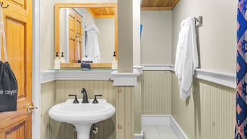 A bathroom with a white sink, wooden paneling, a mirror, and a towel hanging on the wall.