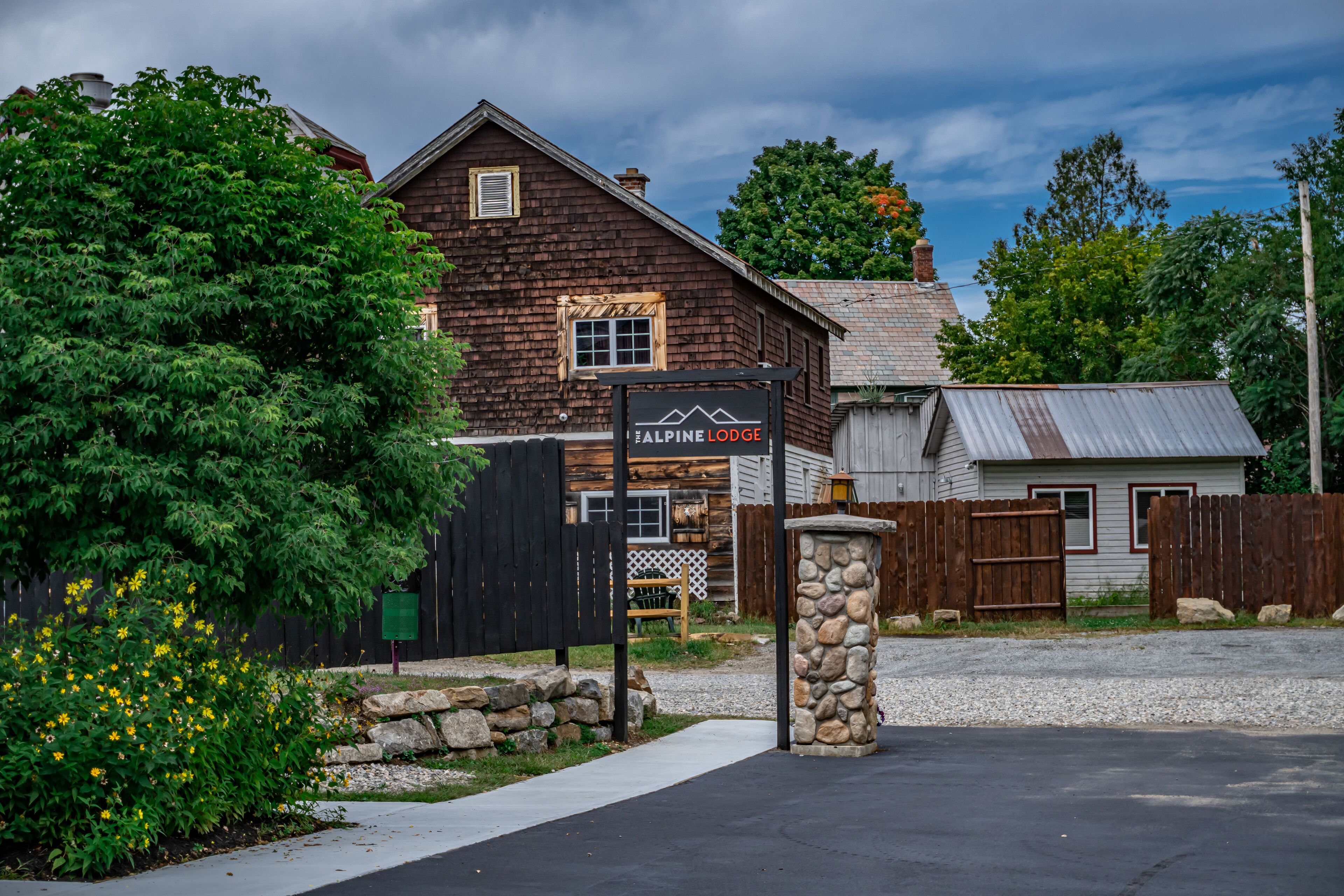 A rustic lodge with a prominent sign, wooden fences, and a stone pillar.