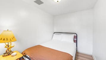 A bedroom with a bed, a bedside table with a lamp, and a wall-mounted light fixture.