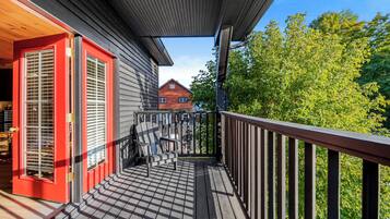 A wooden deck with a red door and a view of a house in the background.