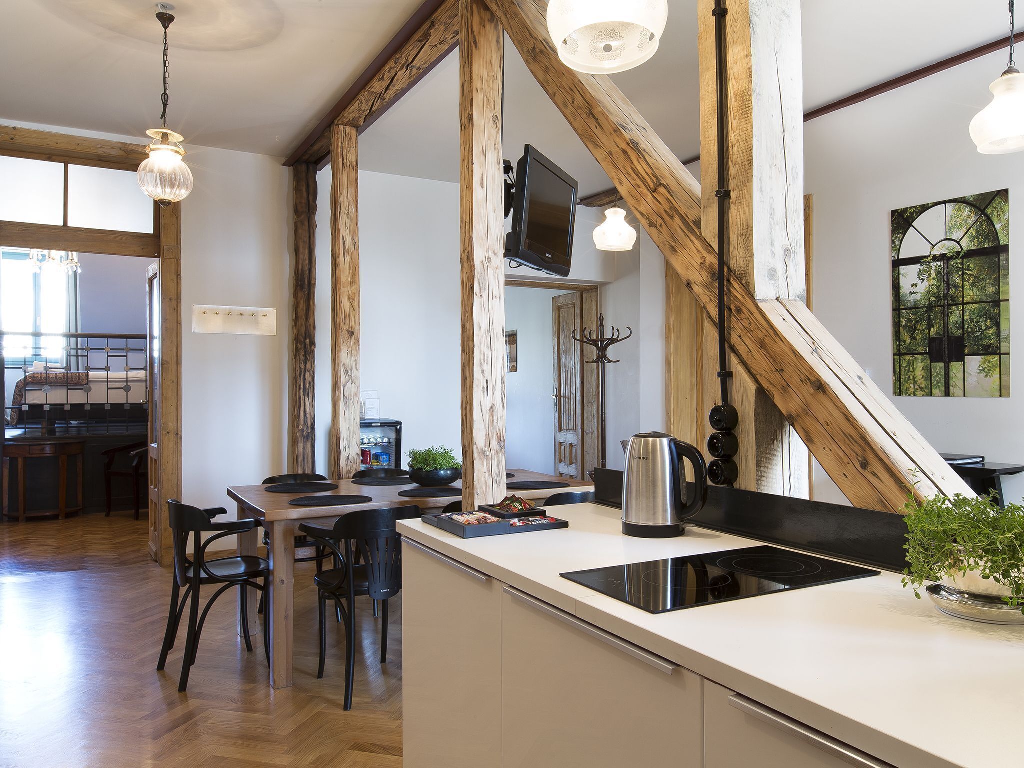Une cuisine moderne dotée d’un îlot central, de poutres en bois et d’un coin repas avec des chaises.