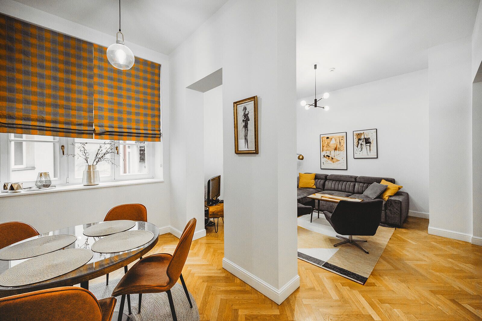 A modern living room with a grey sofa, a dining table with chairs, and a fireplace.