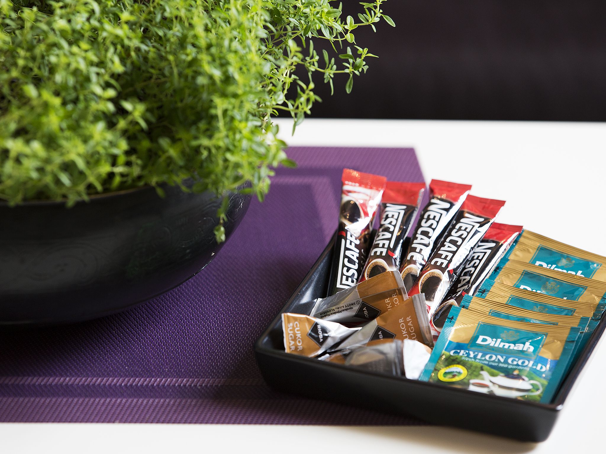 A tray with Nescafe coffee pods and a packet of Dilmah Ceylon Gold tea.