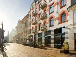 A cobblestone street lined with historic buildings featuring balconies and storefronts.