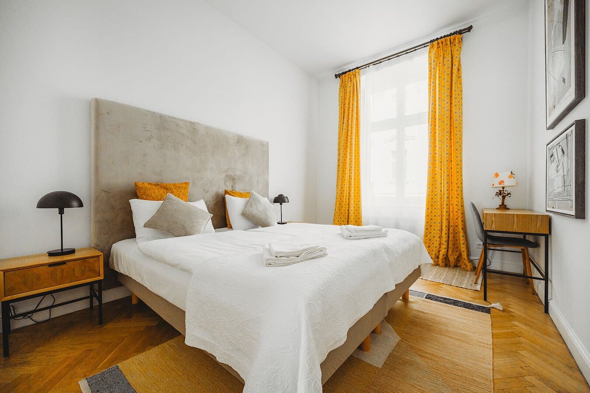 Een moderne slaapkamer met een groot bed, een nachtkastje, een bureau en een stoel.