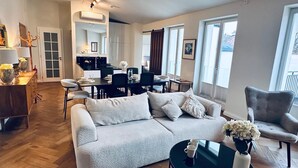 A spacious living room with a sofa, coffee table, and dining area. - Antique Apartments Old Town (Kraków)