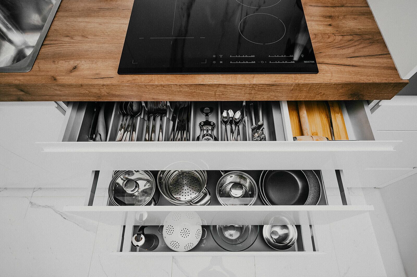 A kitchen drawer with utensils and cookware.