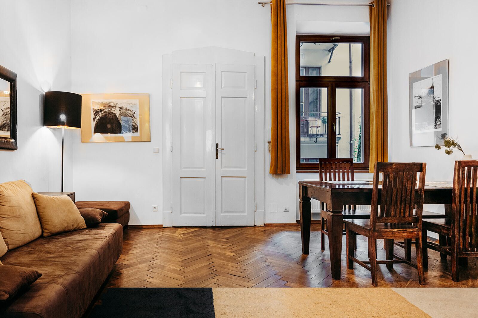 Una sala de estar con un sofá, una mesa de comedor con sillas, una lámpara y una puerta.