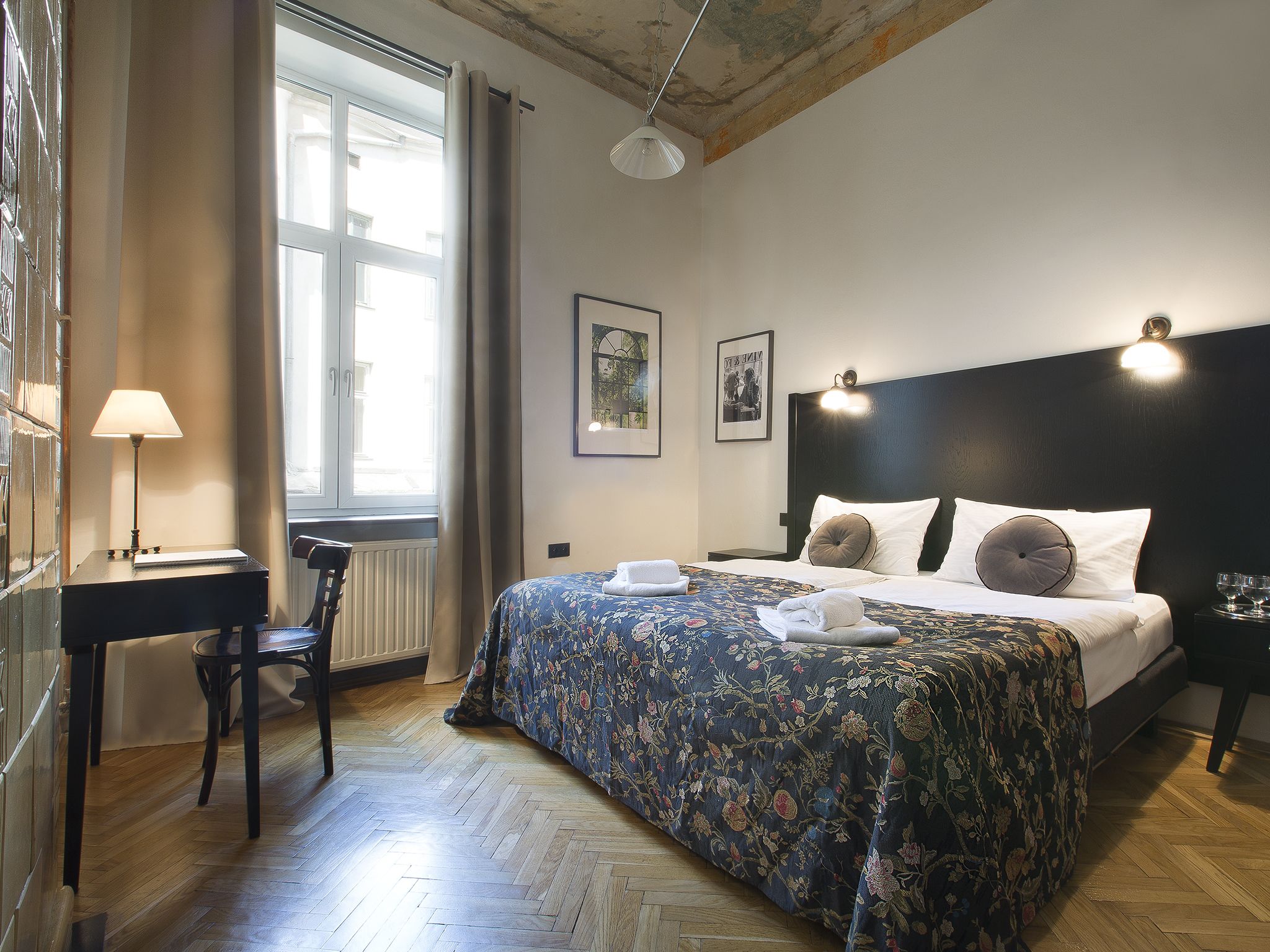 Una habitación de hotel con cama, escritorio, silla, ventana y radiador.