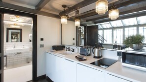 A modern kitchen with a large island, white cabinetry, and a large window providing natural light. - Antique Apartments Old Town (Kraków)