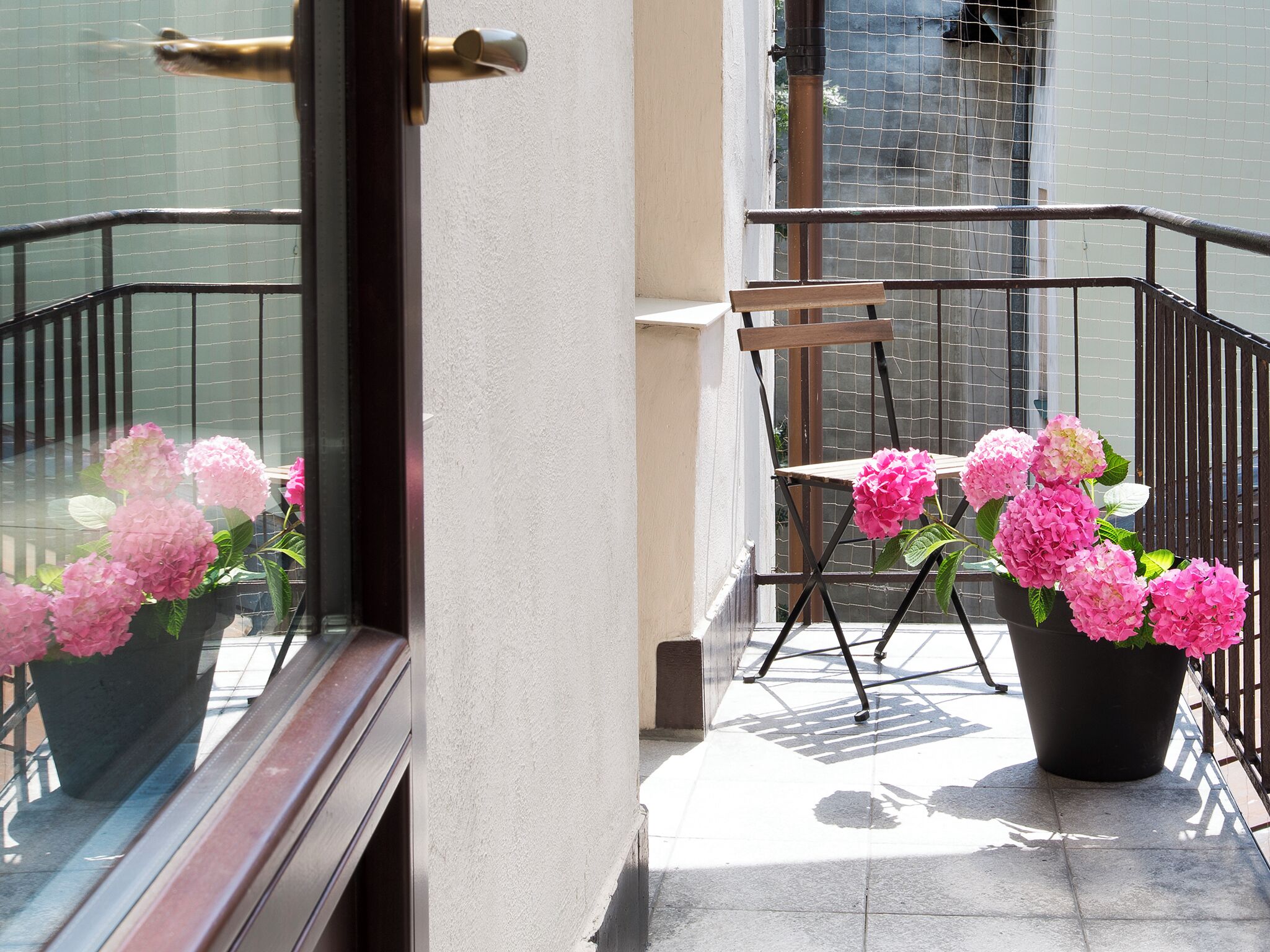 En balkon med en stol og krukker med planter.