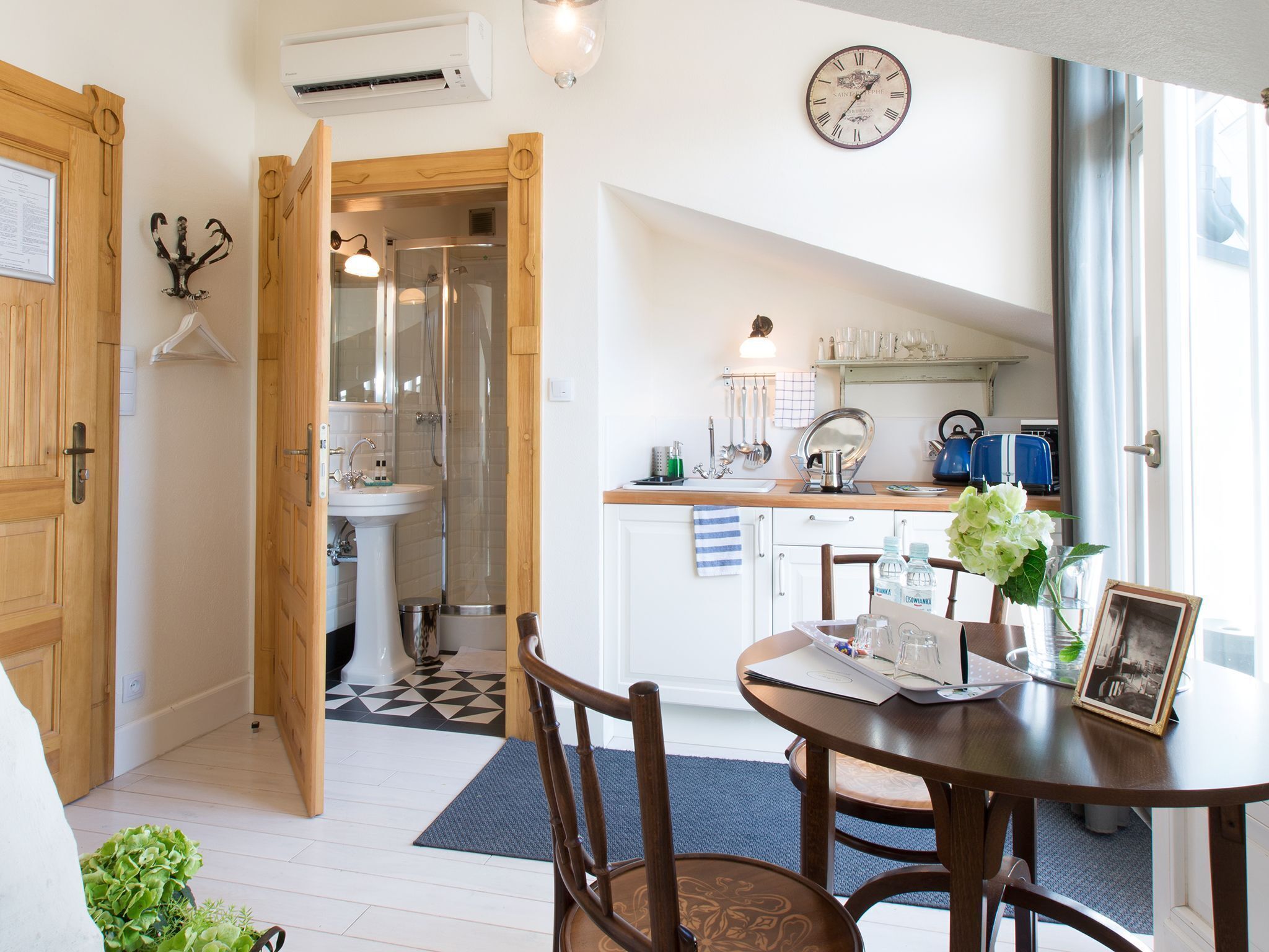 Una cocina moderna con zona de comedor, que incluye una mesa de madera, sillas y un reloj en la pared.
