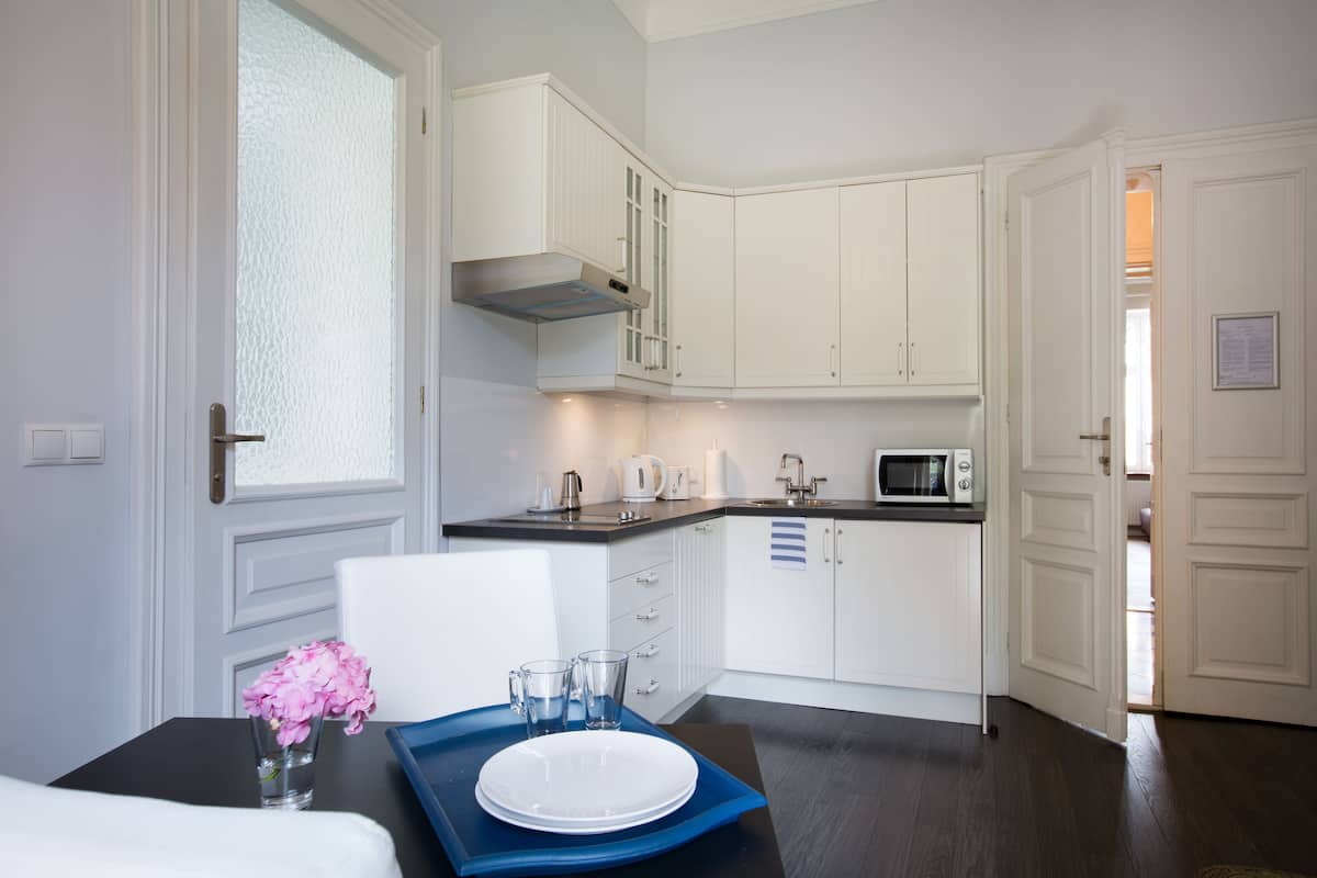 Een moderne keuken met witte kastjes, een zwart aanrecht en een eethoek met een tafel gedekt voor twee personen.
