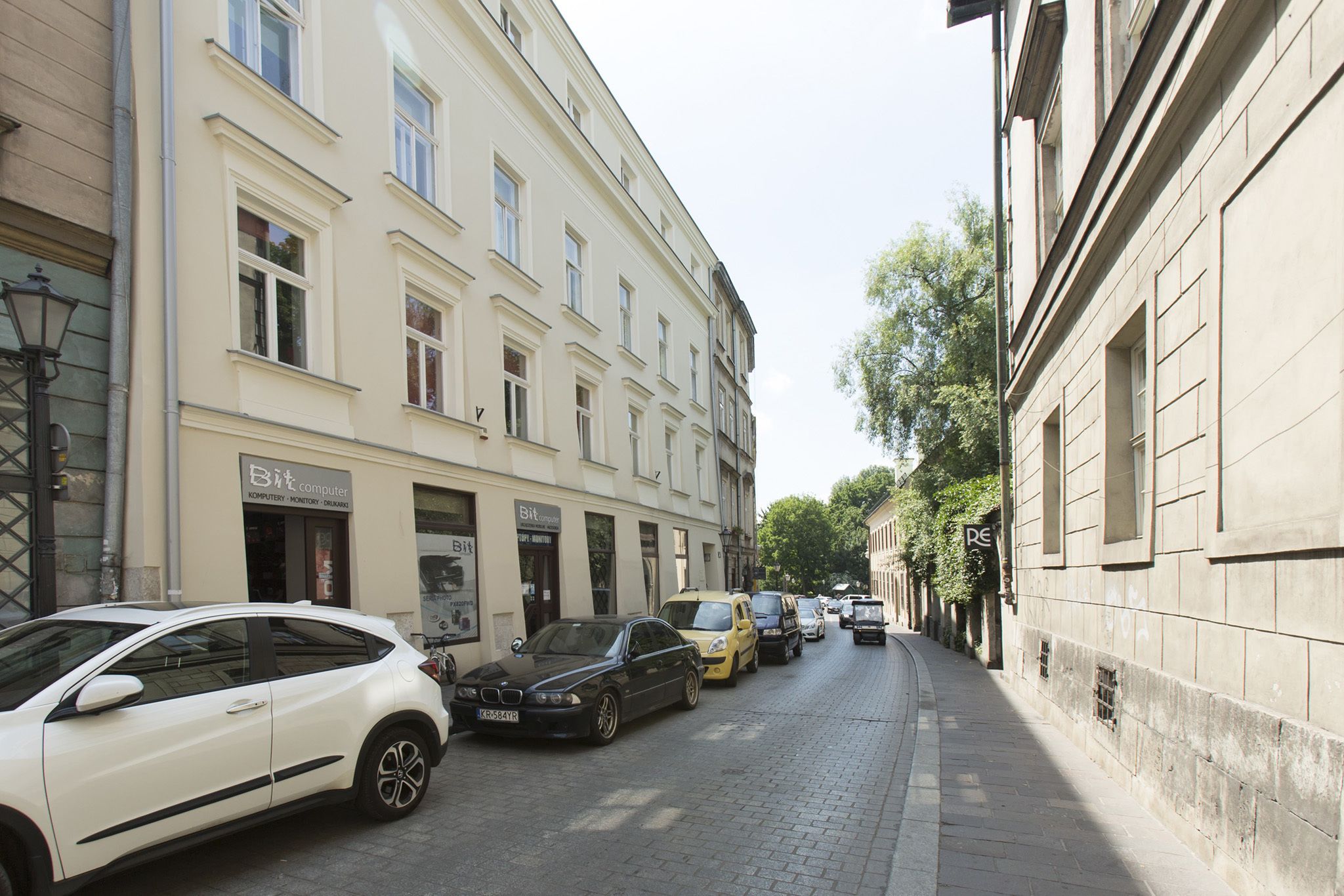 A street lined with parked cars and buildings, including a visible storefront with signage.