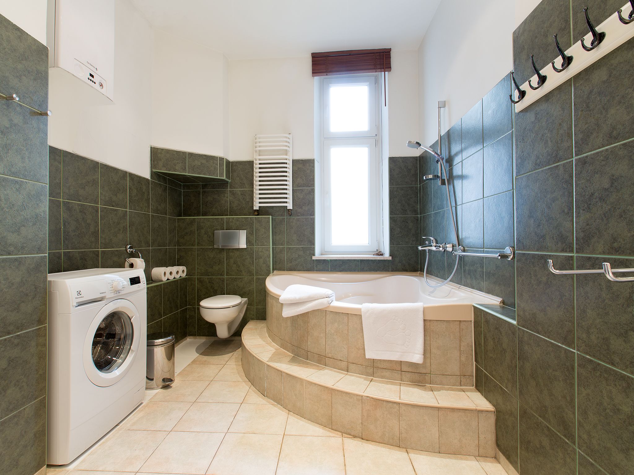 A modern bathroom with a built-in washing machine, a toilet, a bathtub, and a shower.