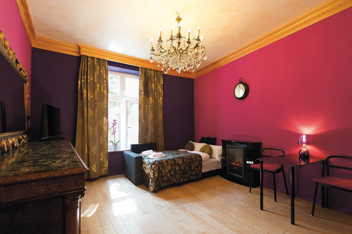 Een kamer met een bed, een bureau, een stoel, een televisie en een kroonluchter.