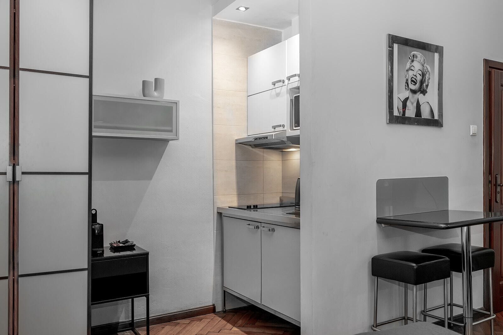 A compact kitchen with a built-in stove, a small countertop, and a bar stool area.