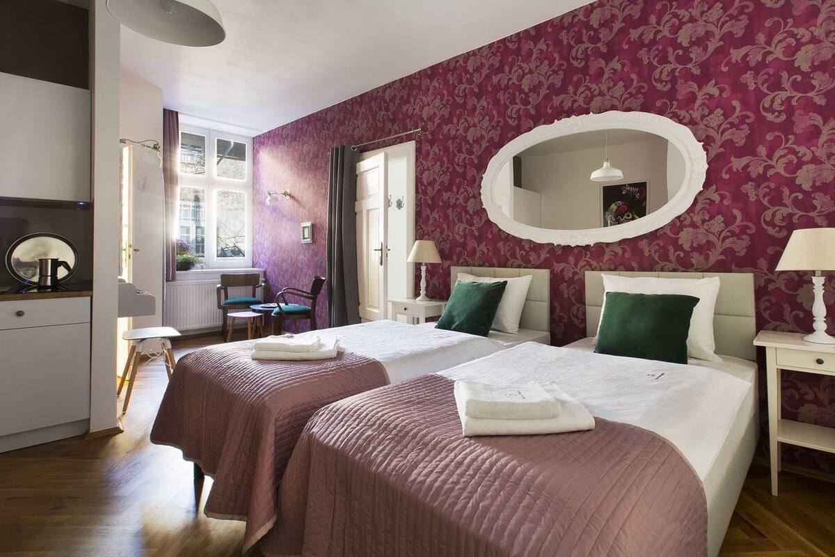 Een slaapkamer met twee bedden, een grote spiegel en een raam met gordijnen.