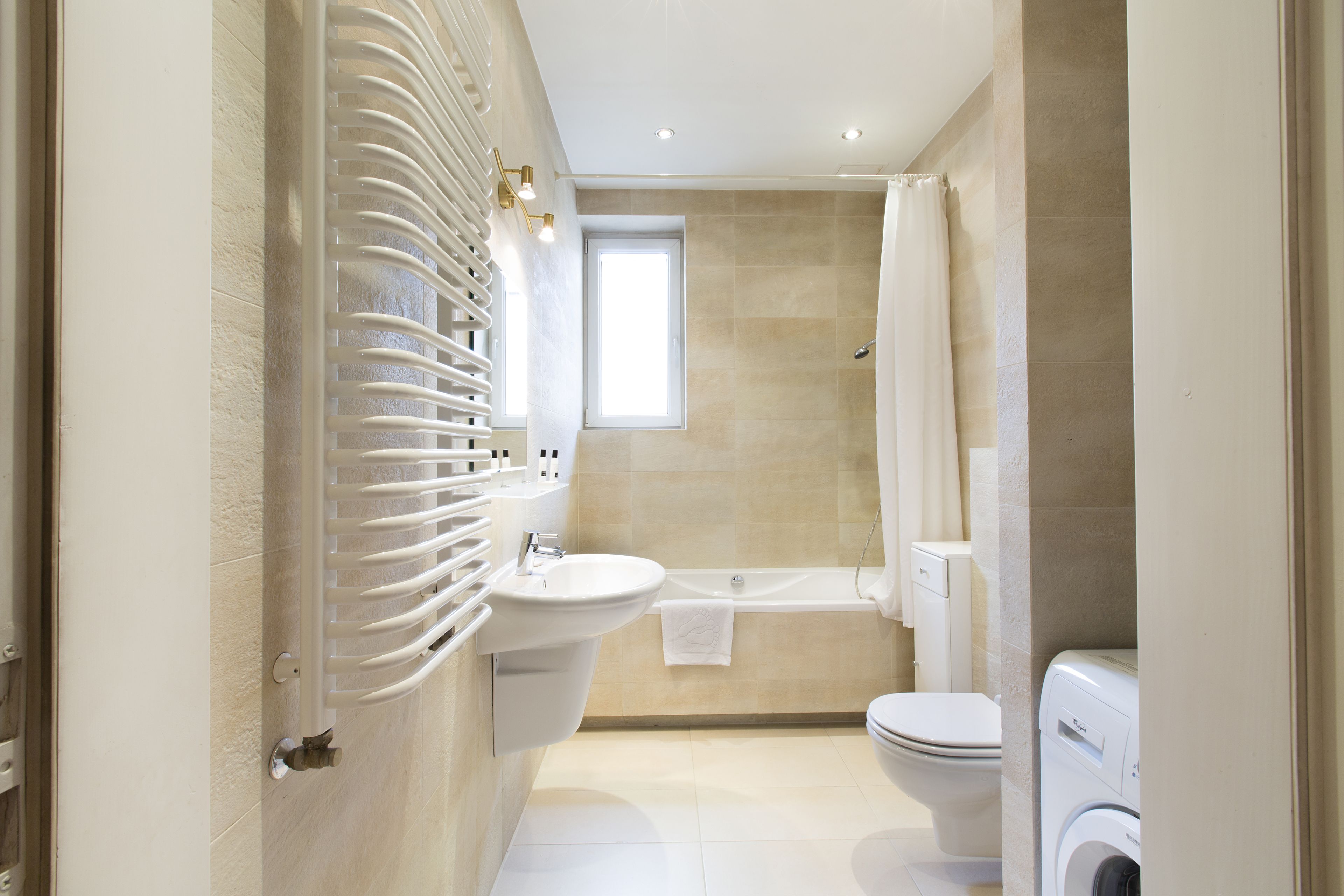 Un baño moderno con lavamanos, inodoro, ducha y lavadora.