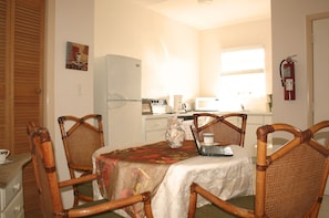 A compact kitchen with a refrigerator, microwave, and coffee maker. There is a dining table with chairs and a fire extinguisher mounted on the wall. - Ocean Pearl Bonefishing Resort (High Rock)