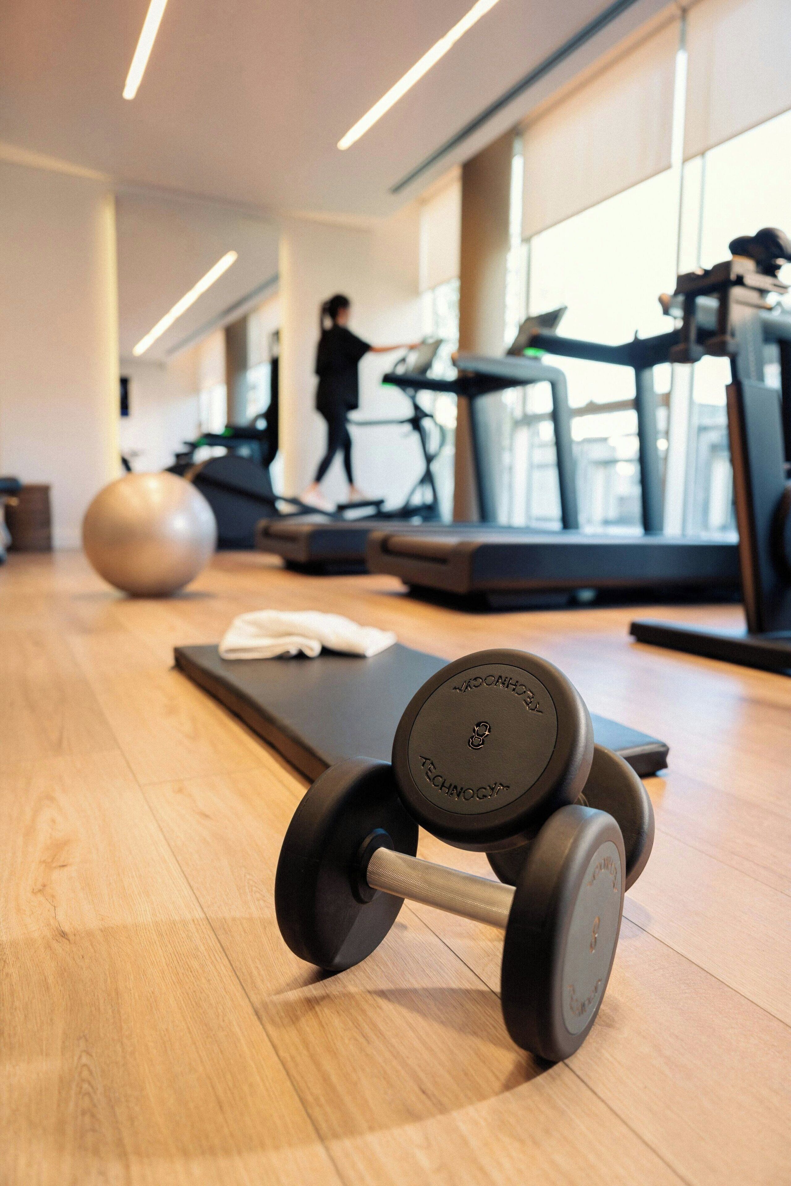 A gym with exercise equipment, including dumbbells, treadmills, and a stationary bike.