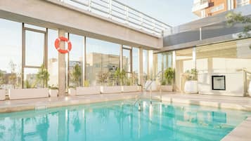 Una piscina en la azotea con un flotador salvavidas, plantas en macetas y vistas a edificios.