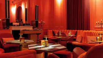 Ein rot gestalteter Lounge-Bereich mit Sitzgelegenheiten, Tischen und einem Kamin.