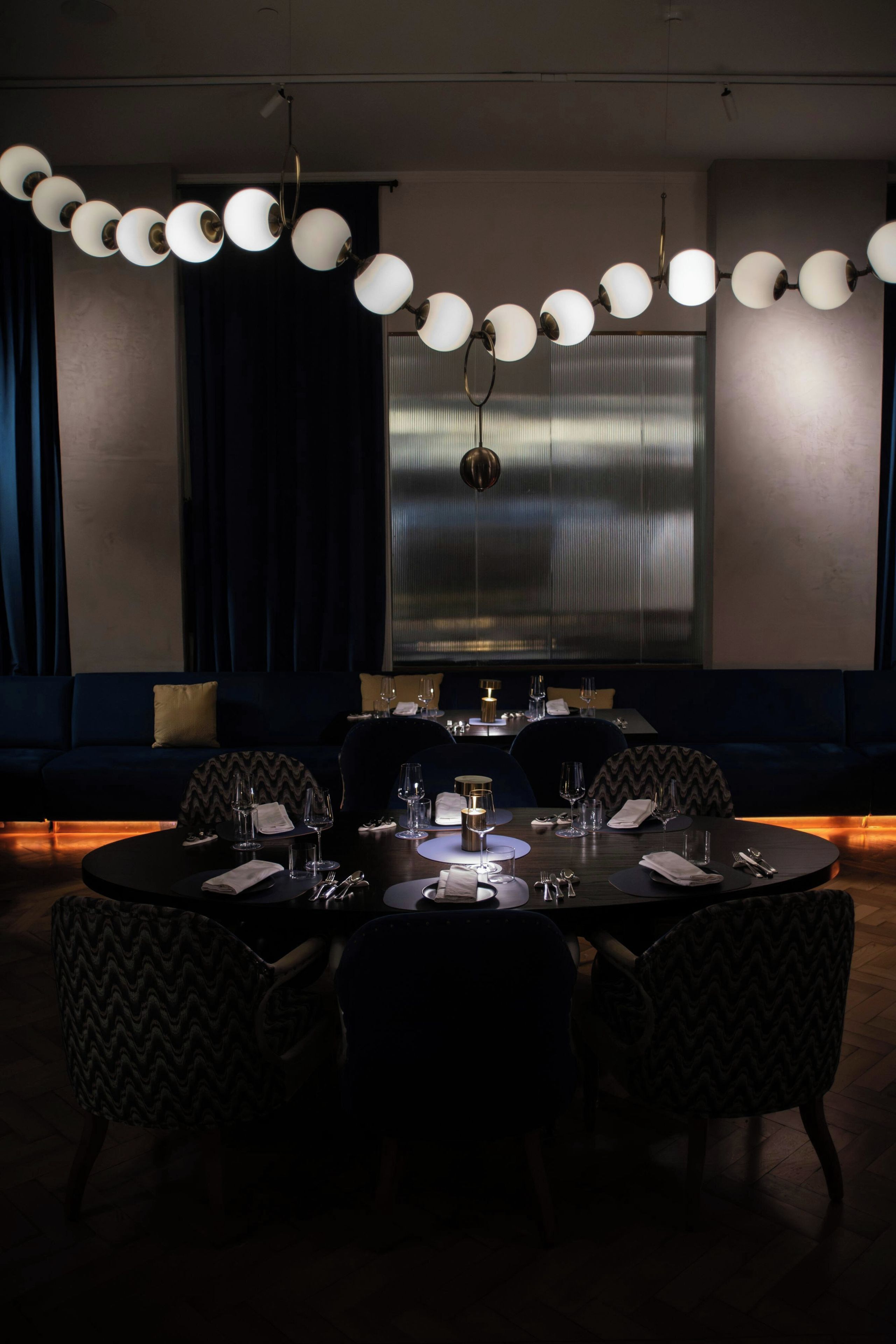 Un coin repas avec une table ronde dressée pour quatre personnes, entourée de chaises.