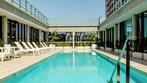A swimming pool with lounge chairs and a view of a cityscape. - Recoleta Grand, a Tribute Portfolio Hotel (Buenos Aires)
