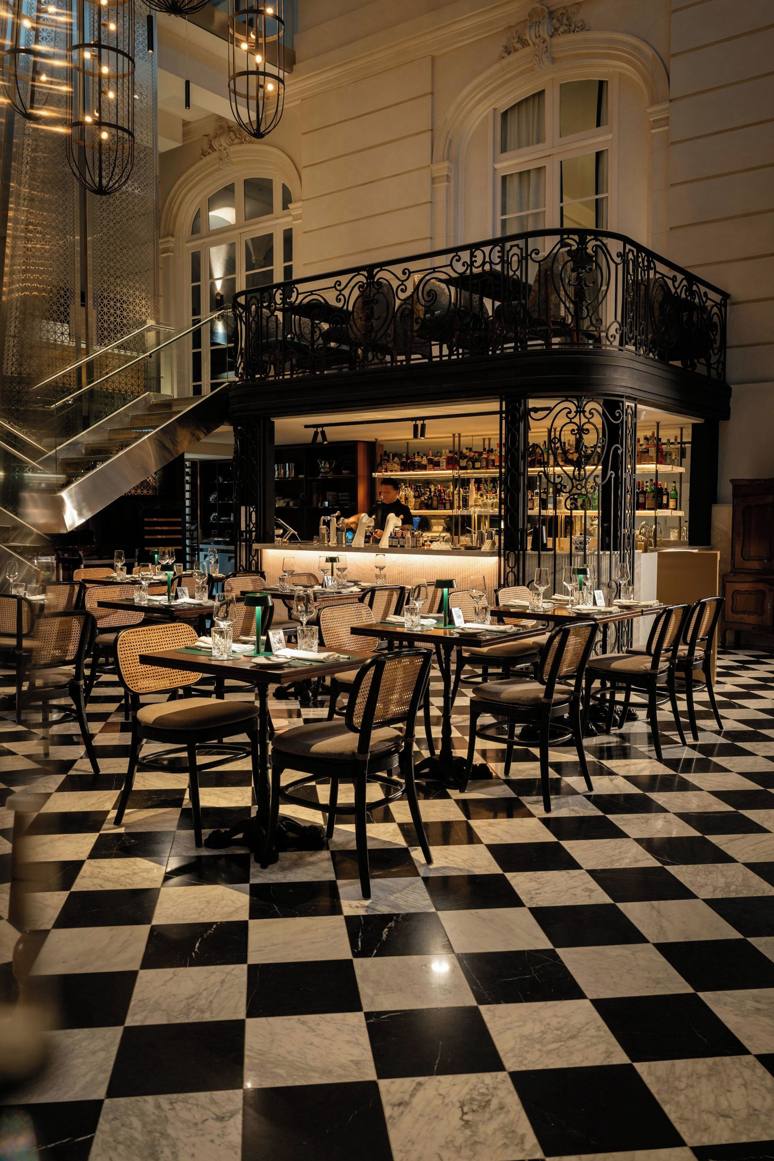 Ein Restaurant mit Schachbrettmuster-Boden, einer Bar und einer Treppe zu einer erhöhten Ebene.