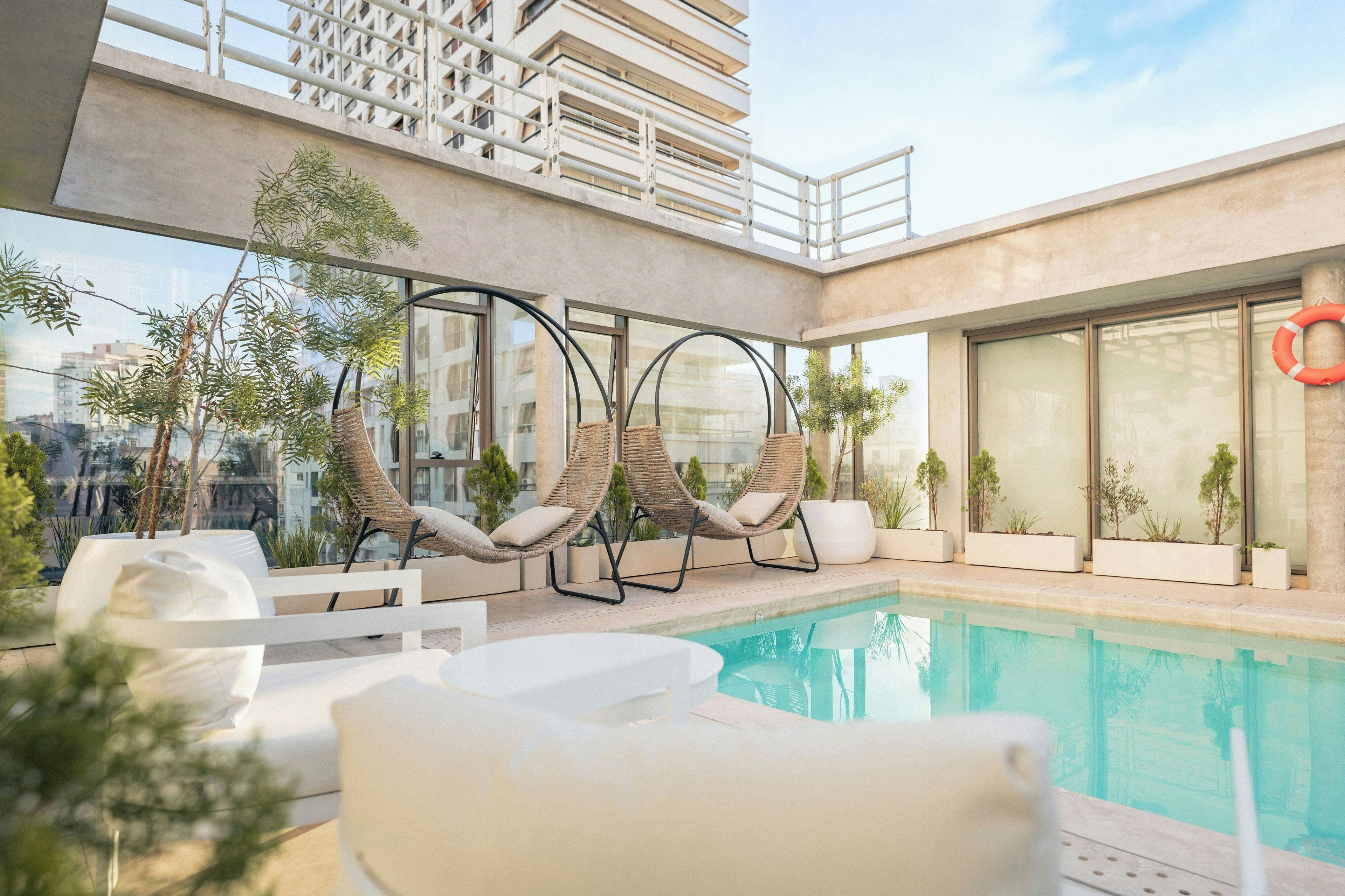 A rooftop pool area with lounge chairs and potted plants.