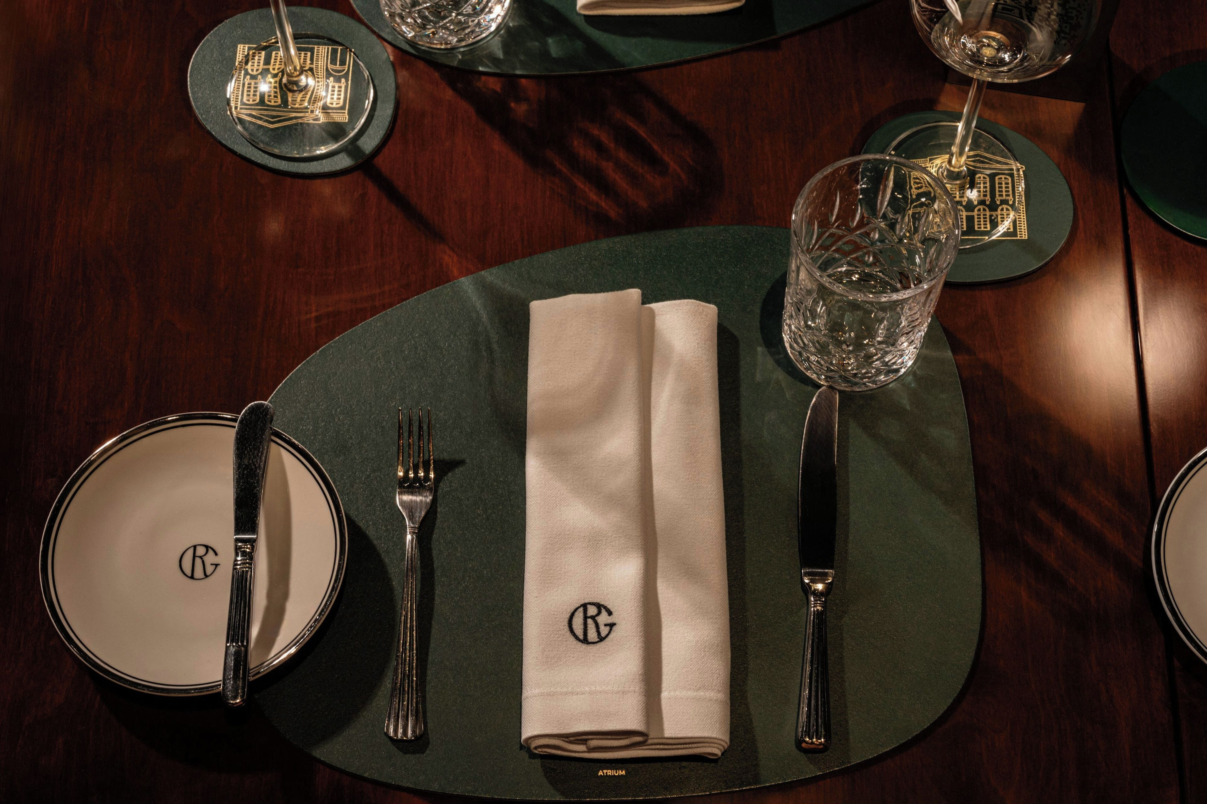 A table set with a folded napkin, cutlery, and a glass.