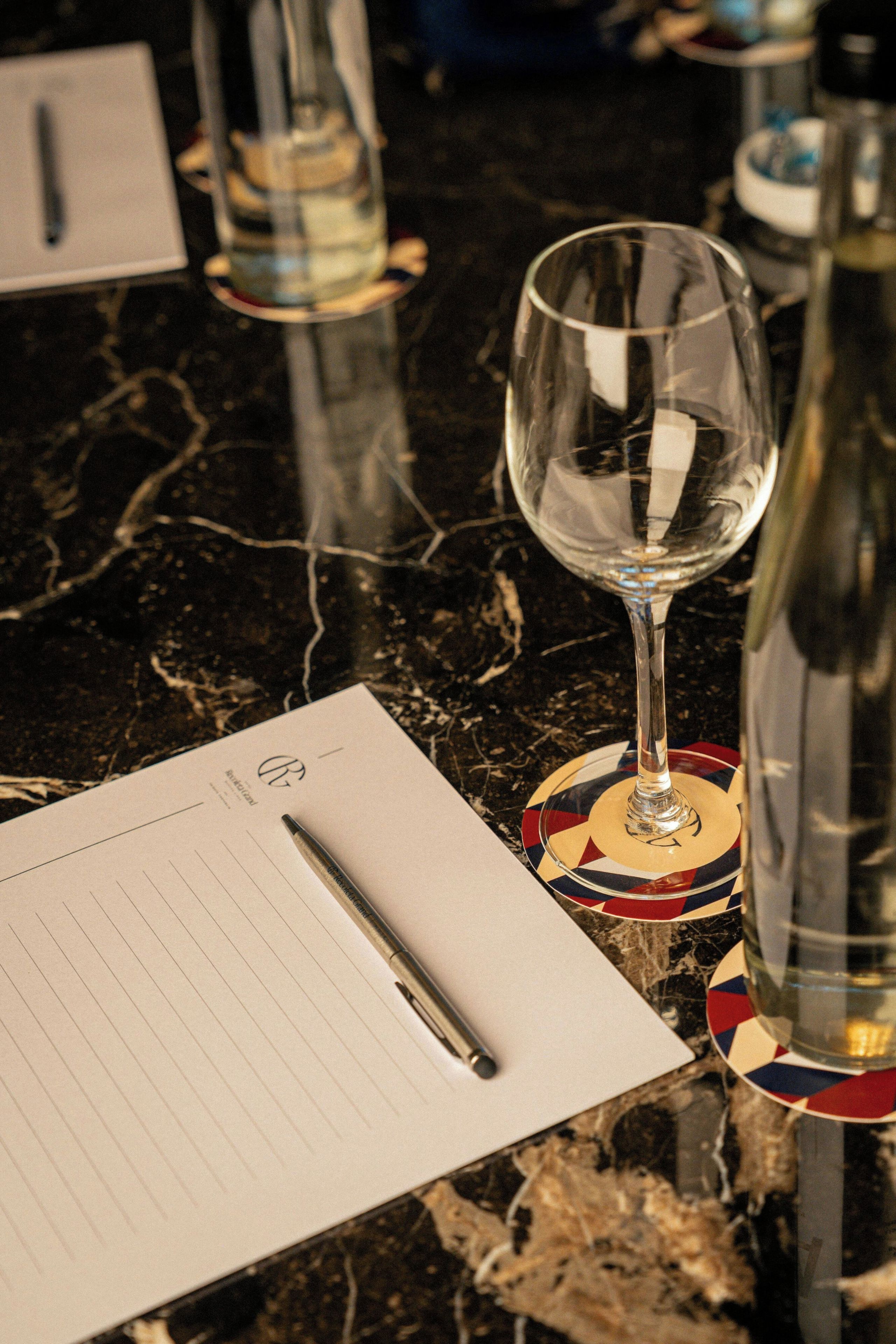 Une table avec un verre d’eau, un stylo et un bloc-notes.