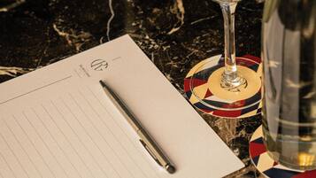 A table with a glass of water, a pen, and a notepad.