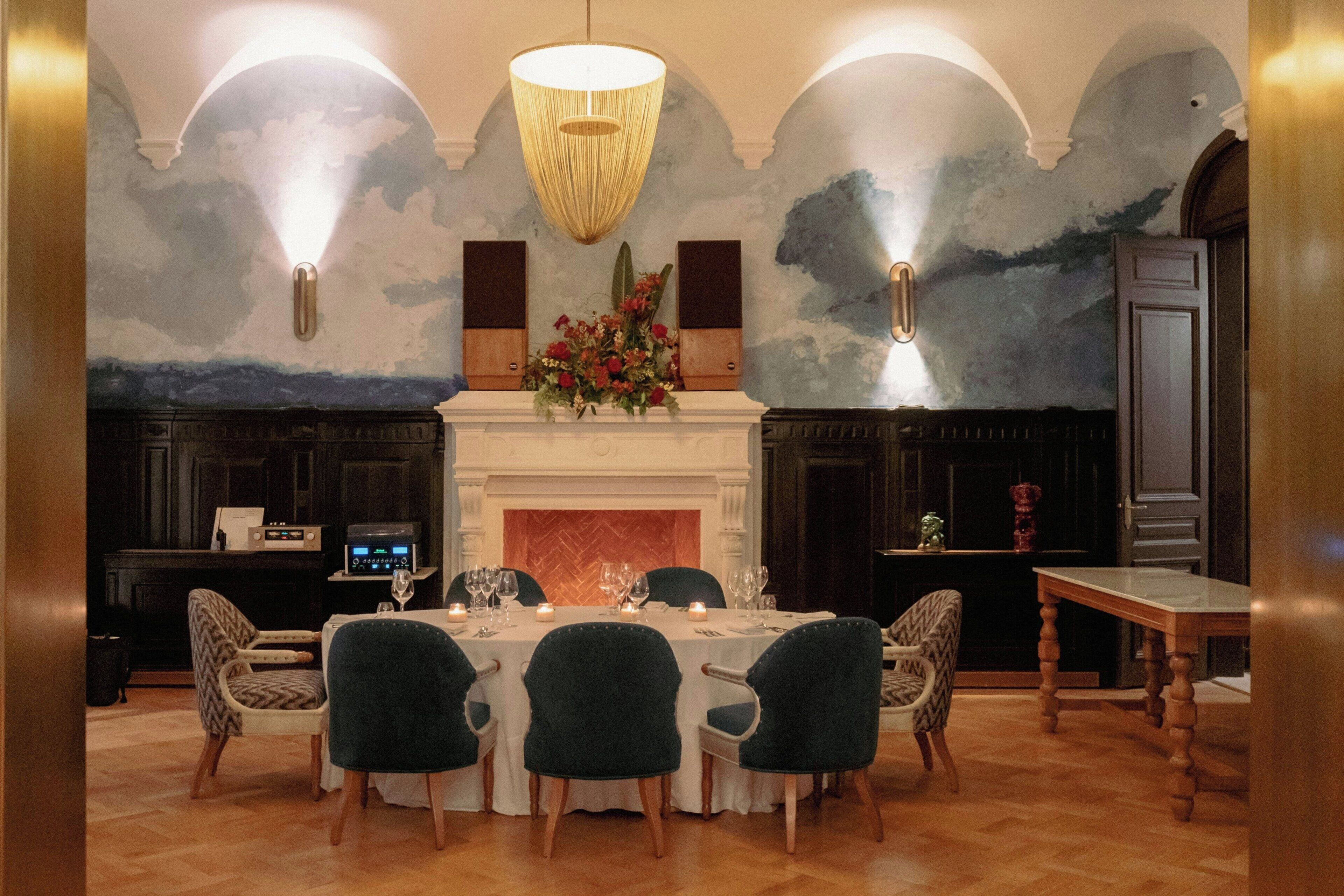 Un comedor con una mesa redonda, sillas, una chimenea y un techo decorativo.