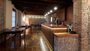 A rustic bar area with a stone wall, wooden ceiling beams, and a bar counter.